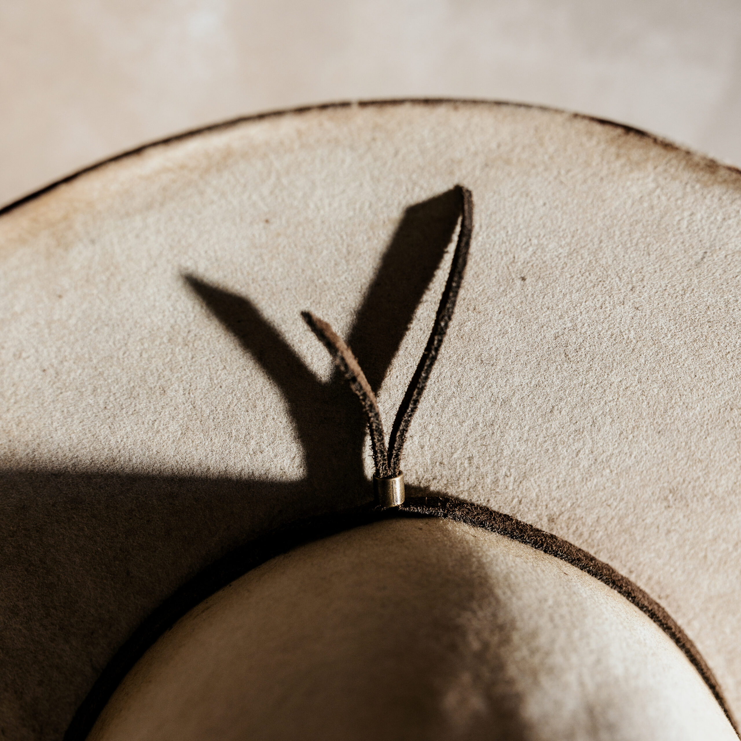 Crown of the Vagabond handcrafted hat customised by Ruth and Chris with traditional tools made in Mallorca, Porto Cristo. Oasis shaped in Vanilla with a curled Brim and a simple brown Leather Band around the crown fixed in the back with a bronze beet. It has a Laser-engraving of a Turtle on the crown top as well as cutouts and burn marks.