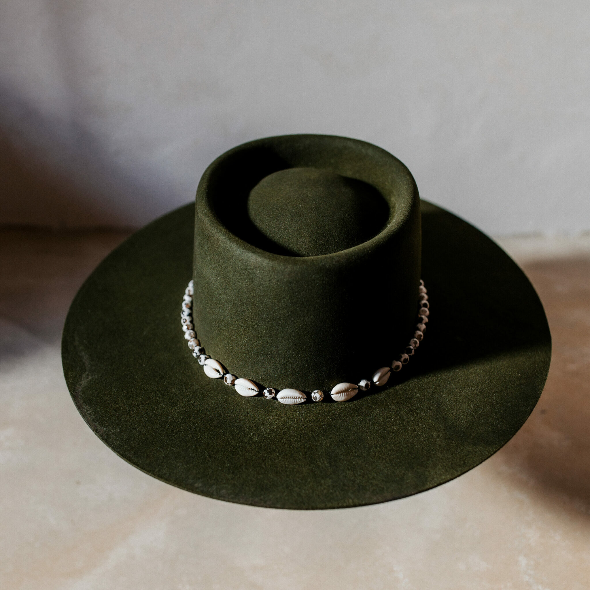 A beautifully handcrafted Crown of the Vagabond hat by the hatters Ruth and Chris on Mallorca with traditional tools in the color Sequoia shaped in Oasis with a clean simple look consisting of edged black-white pearls separated by small black beets and shells in the front with a clean flat brim - branded with the serial number 25.