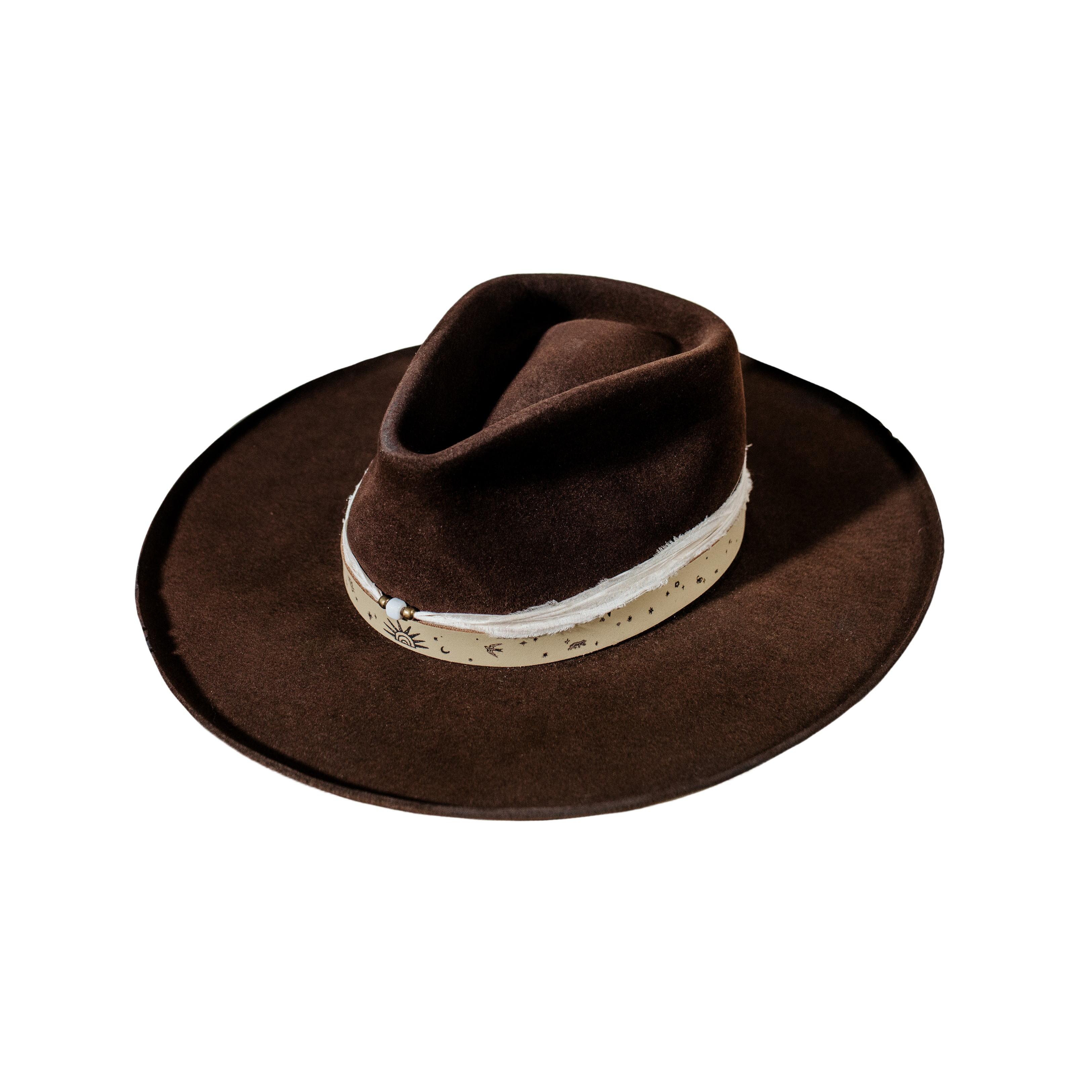 A beautifully handcrafted Crown of the Vagabond hat by the hatters Ruth and Chris on Mallorca with traditional tools in the color Xocolatl shaped in Gold Digger with a western touch mostly clean consisting of a greenish leather band branded with custom laserengraving tied in the back and a recycled seri silk threaded with a white pearl surrounded by little golden pearls on top. The curled brim has cutouts, the hat is filled with a custom lining and is branded with „Neri“ and the serial number 26 on the sweatband.