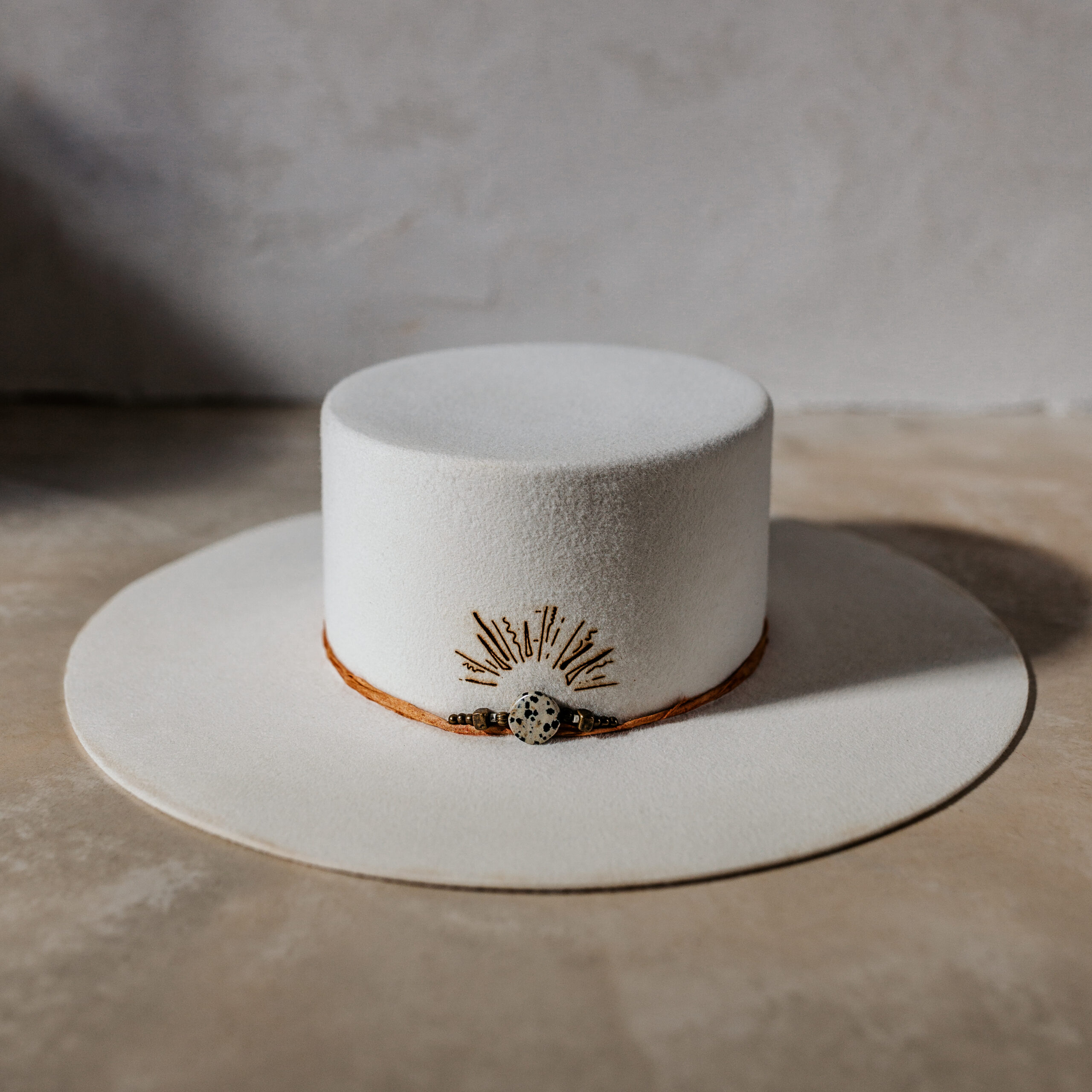 A beautifully handcrafted Crown of the Vagabond hat by the hatters Ruth and Chris on Mallorca with traditional tools in the color Snow shaped in Venice with a clean stunning look. The design is made of copper-colored sari silk and a centred build up stone threat highlighted with a handdrawn custom laser branding. The hat has a clean flat 10cm/3.94in brim and is branded with the serial number 30 on the sweatband.