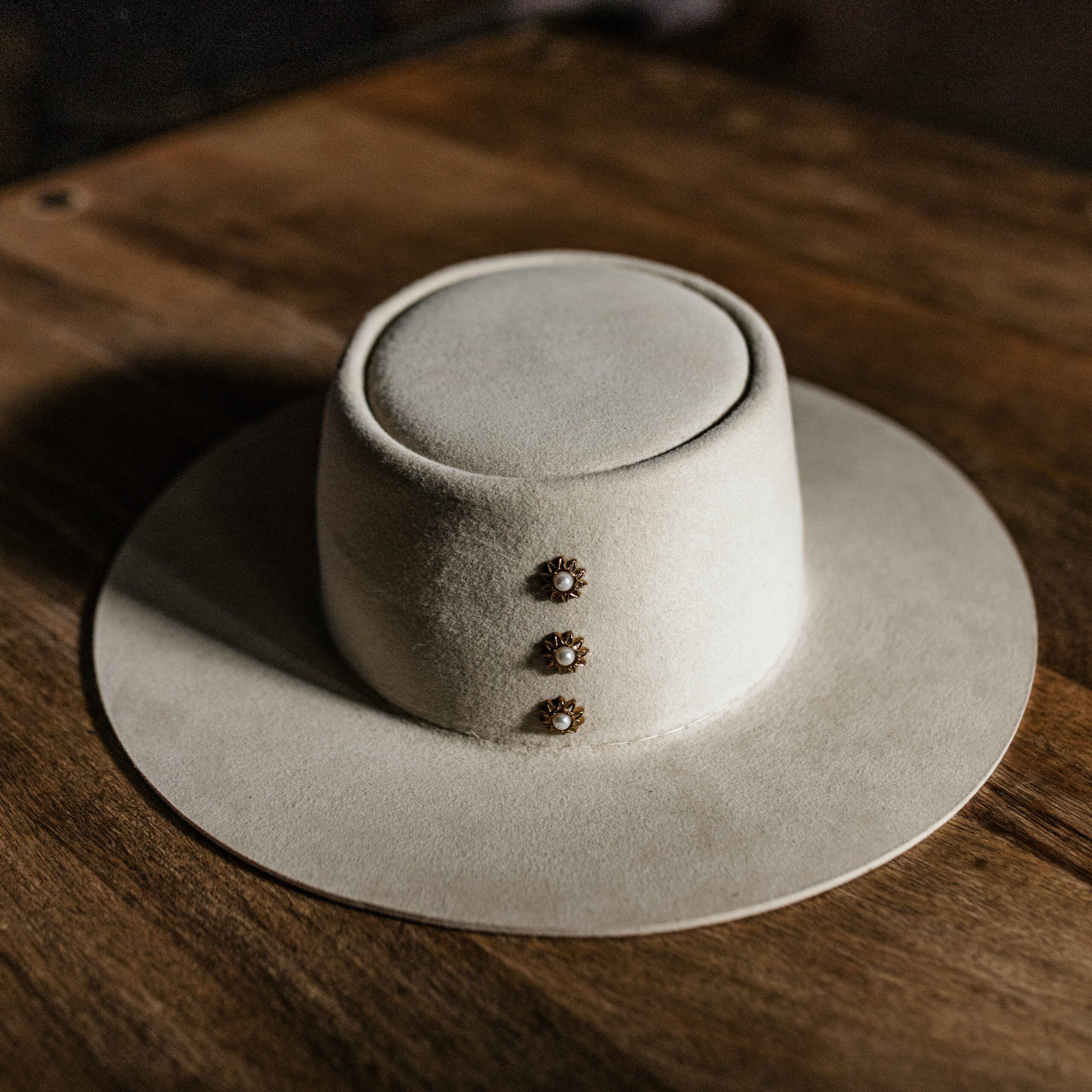 Crown of the Vagabond hat on Mallorca in color Bone Oasis-shaped. Centred golden pearl rivets and a clean flat 8cm / 3.14in brim.