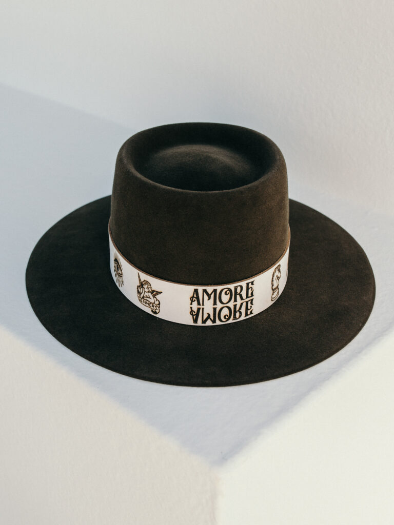 Amore - for all true basherts. Color Tortuga comes in an Oasis shape. Stylish leather hatband crested with hand-drawn signature Tattoos.